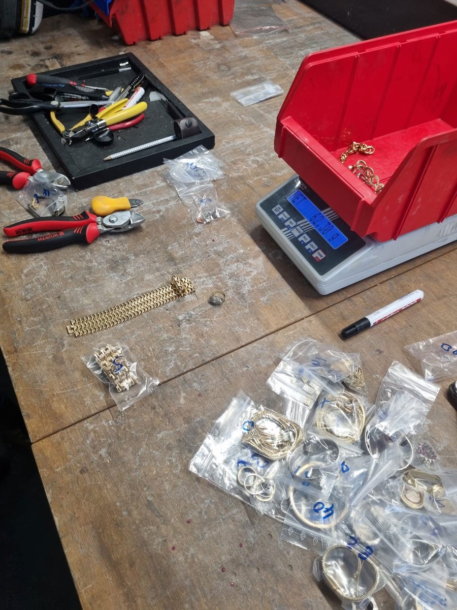Goldschmuck und Altgold in Beuteln auf einer Werkbank neben einer Waage vor dem Einschmelzen